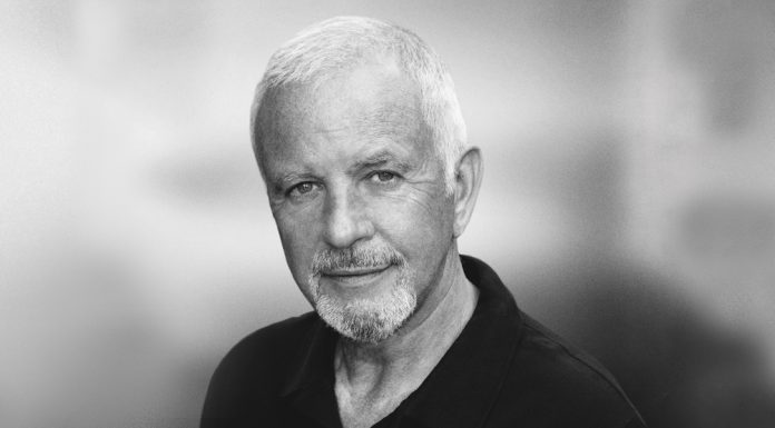 David Essex David Essex - Older man with short gray hair and a mustache, wearing a black shirt against a blurred background.